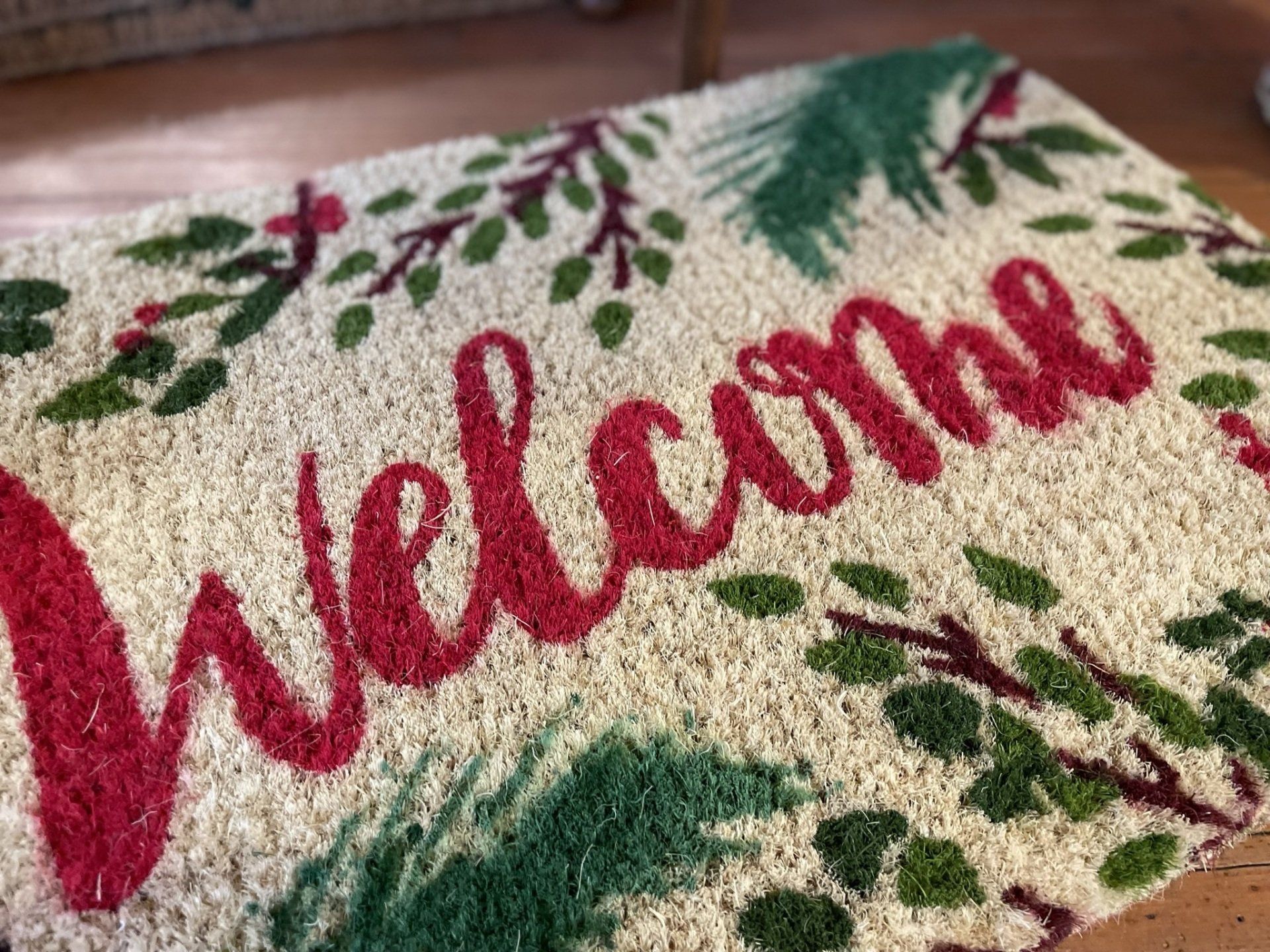 A welcome mat with red and green leaves on it