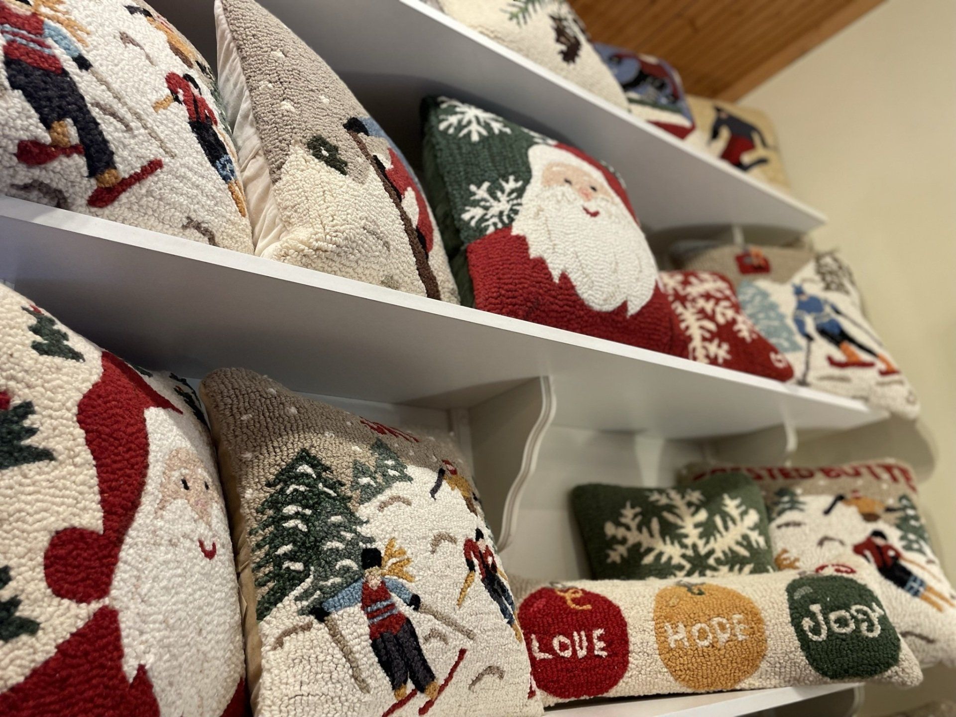 A shelf filled with a variety of christmas pillows