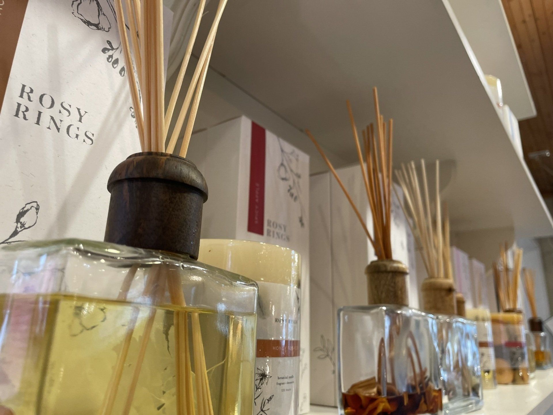 A shelf filled with bottles of reed diffusers and candles.