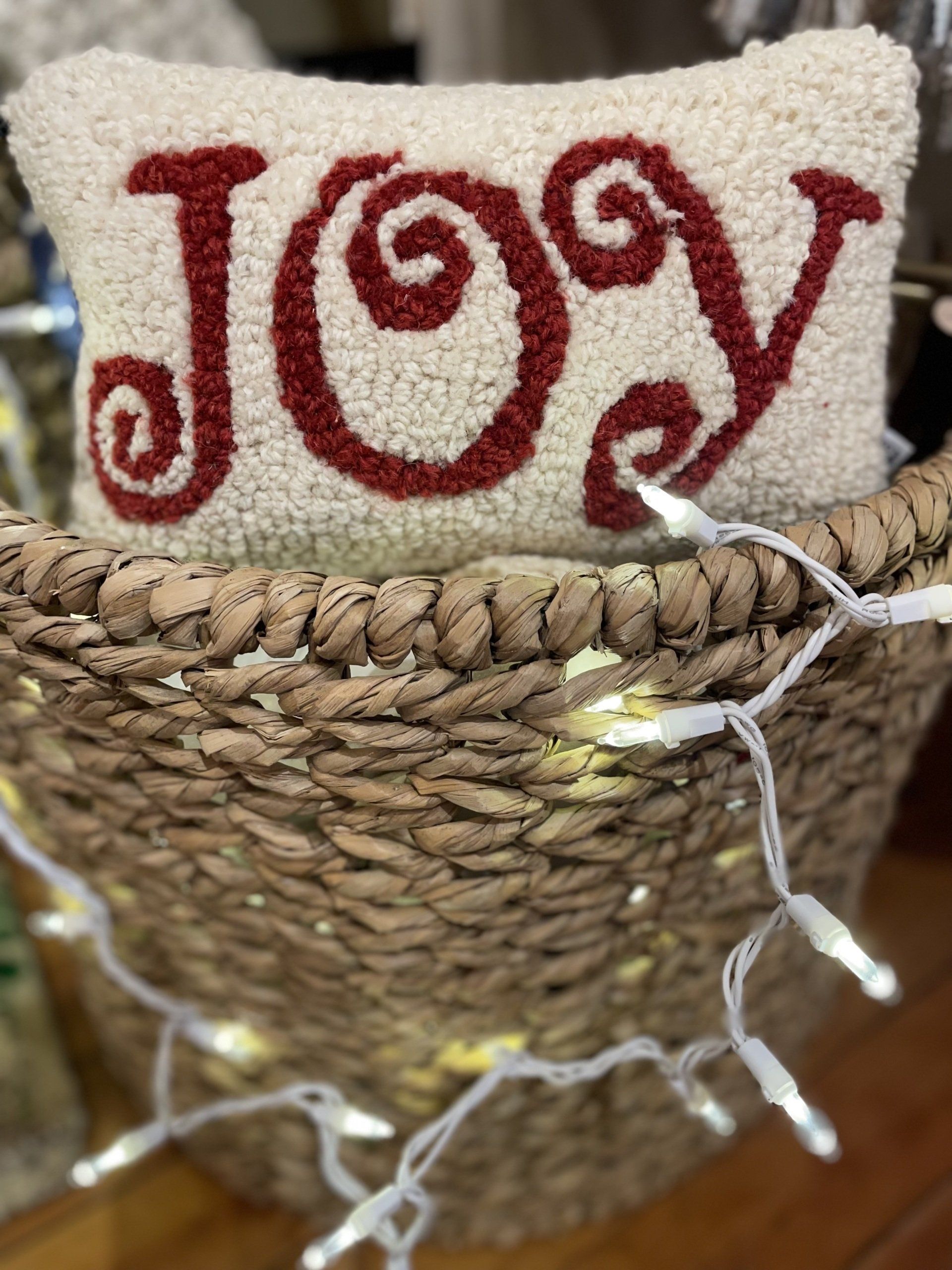 A pillow with the word joy written on it is sitting in a basket.