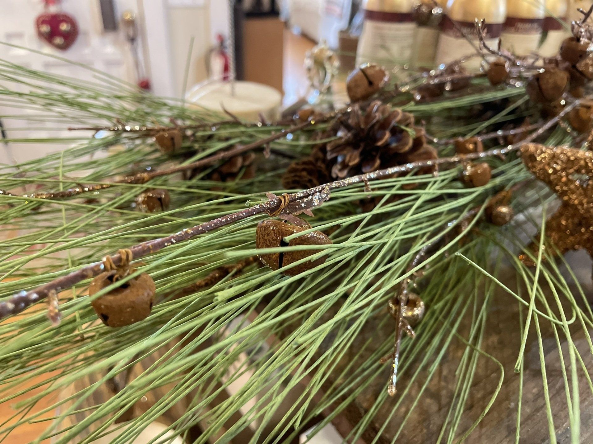 A close up of a wreath with pine cones and candles on a table.
