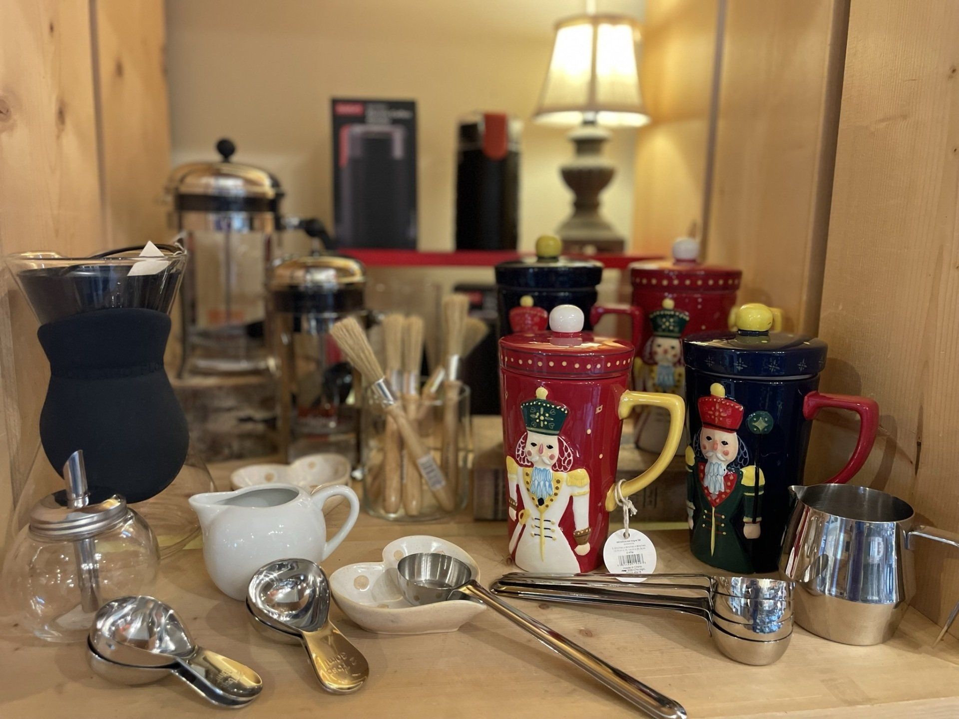 A wooden shelf filled with a variety of kitchen utensils and cups.
