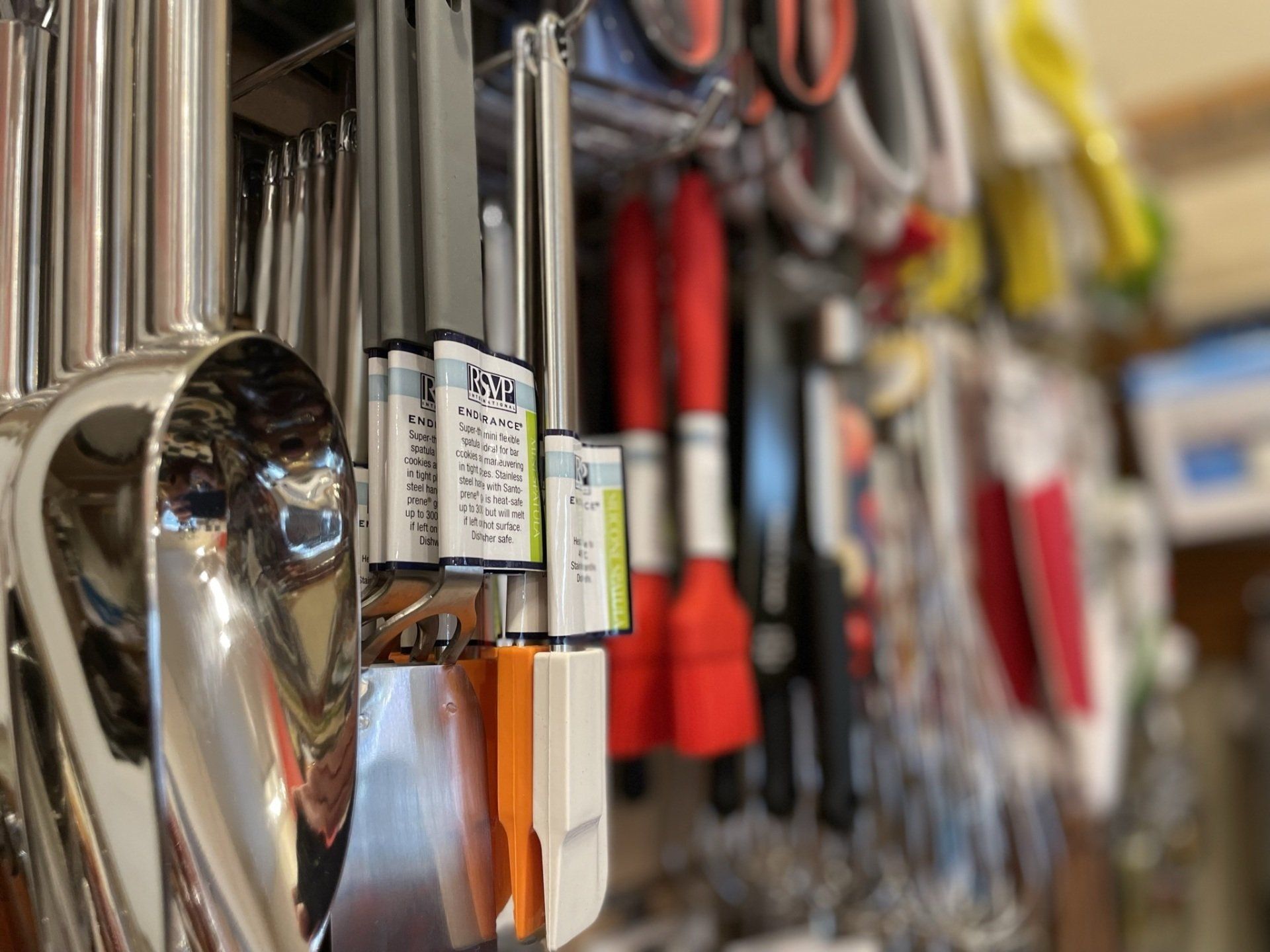 A bunch of kitchen utensils hanging on a wall in a store.