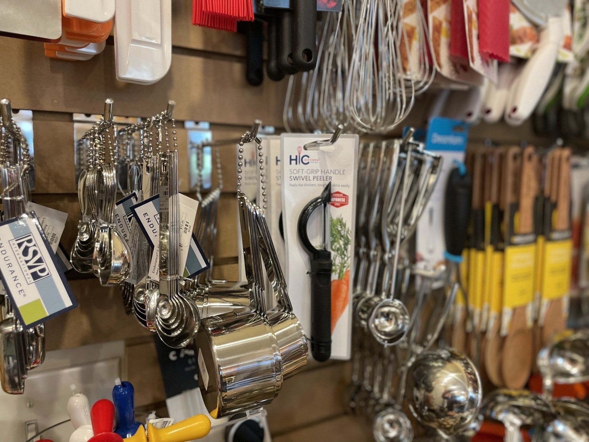 A variety of kitchen utensils are hanging on a wall in a store.