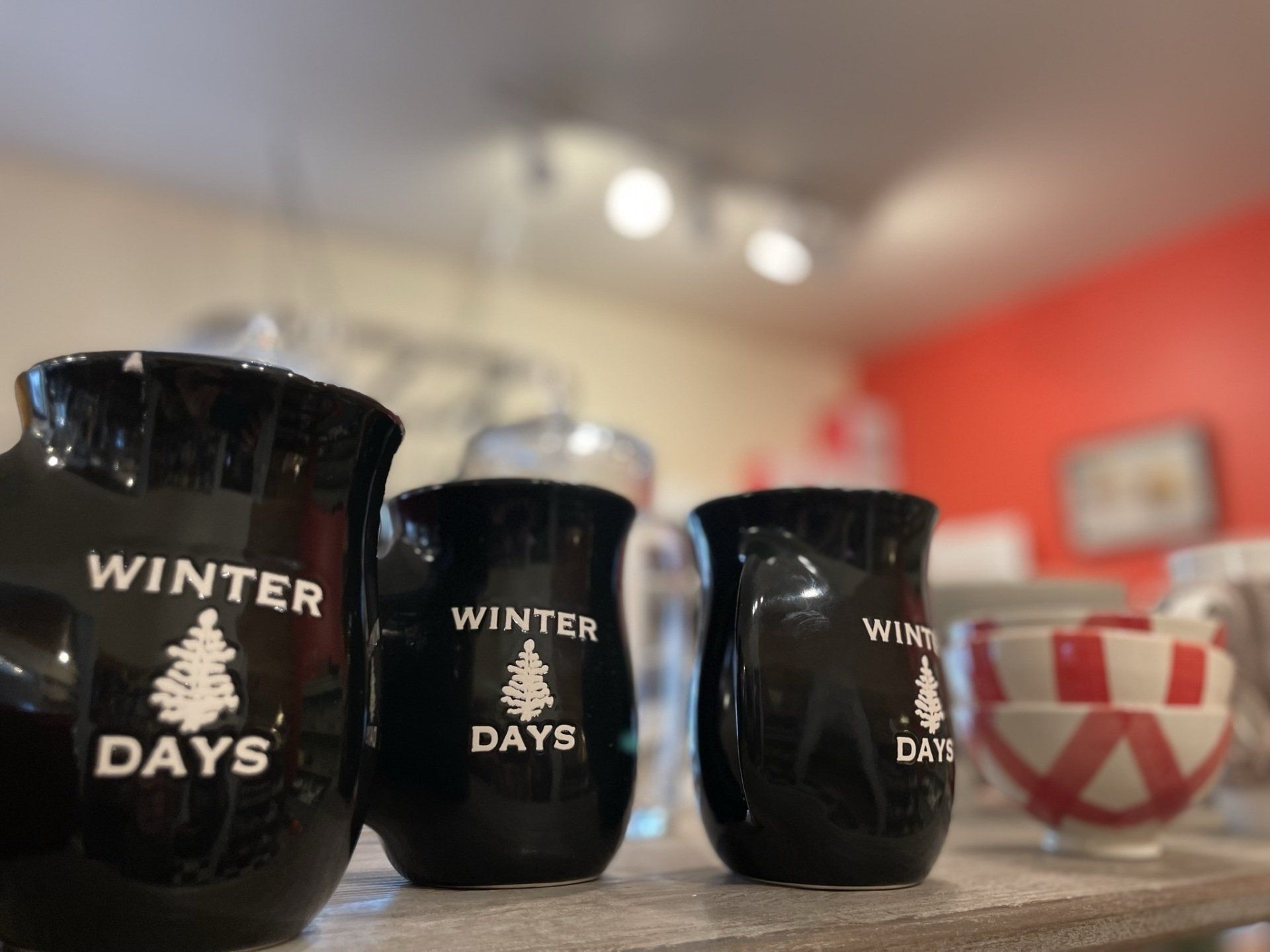 Three black winter days mugs are sitting on a shelf