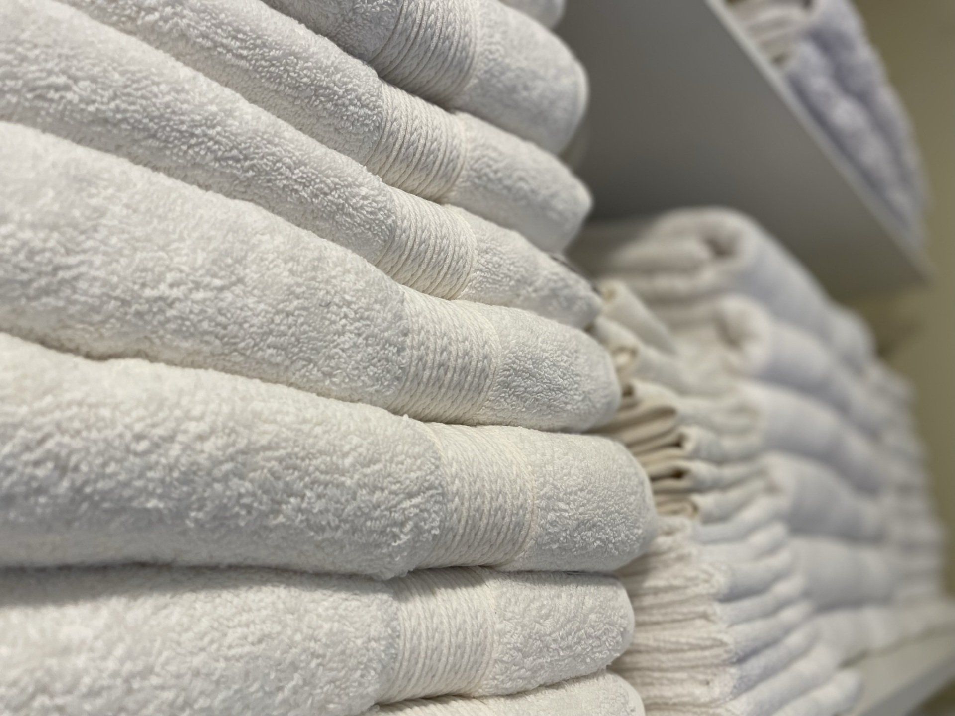 A stack of white towels sitting on top of each other on a shelf.