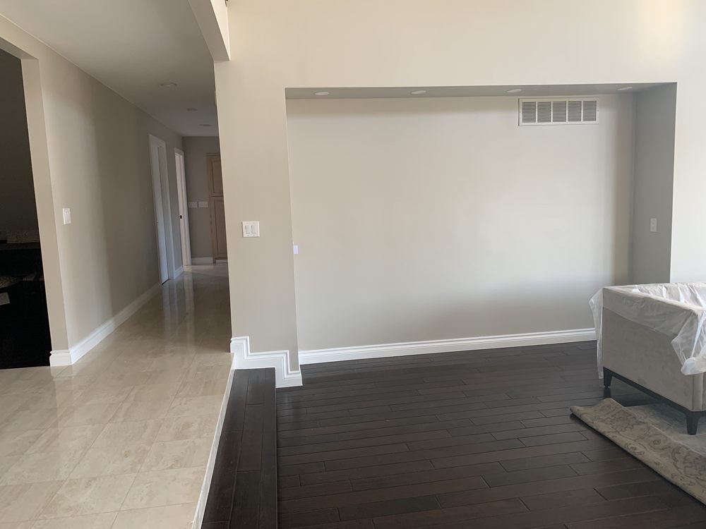 Interior view of a house with hallway, hardwood floors, beige walls, and a living area.