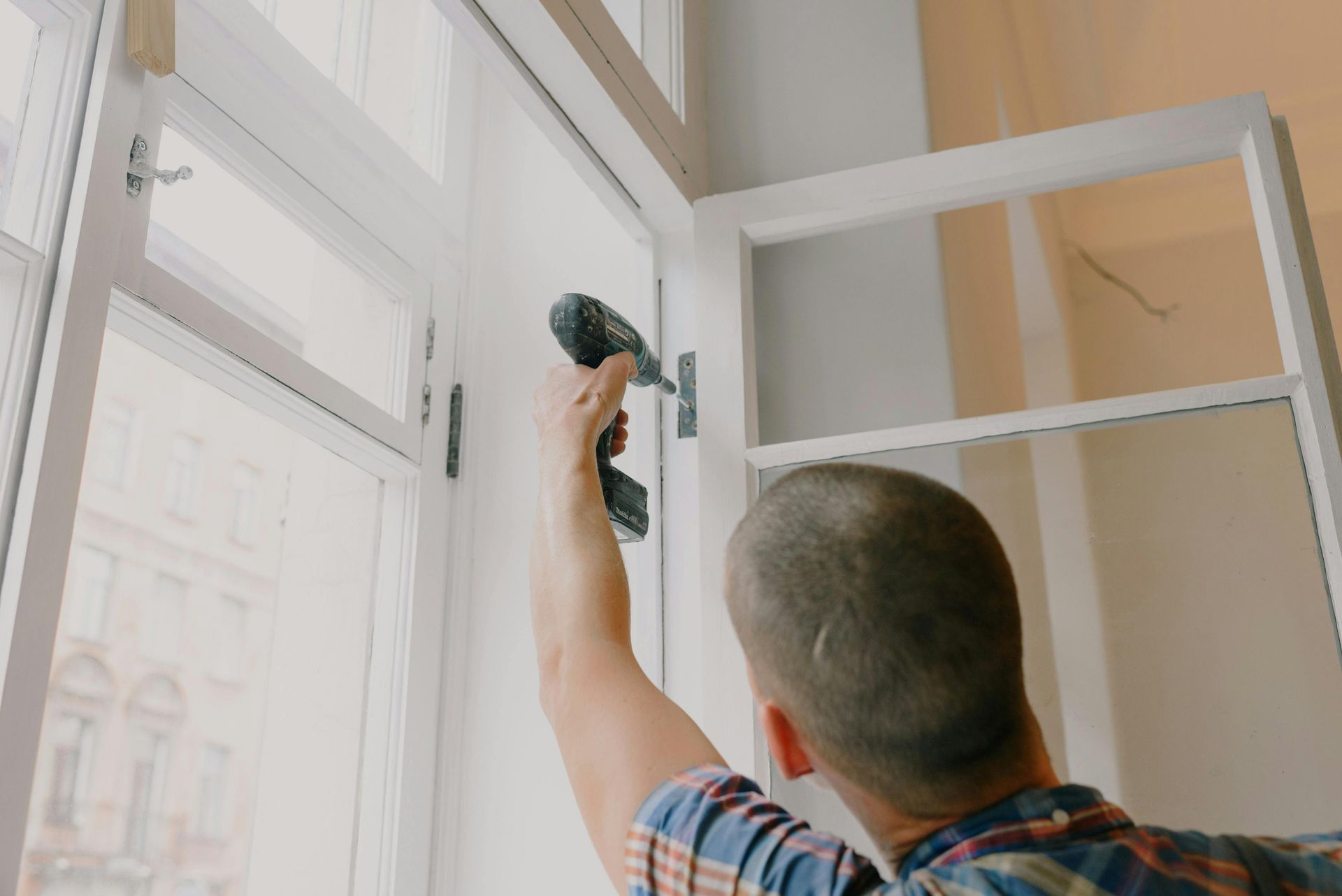 Person applying sealant to a white door frame.