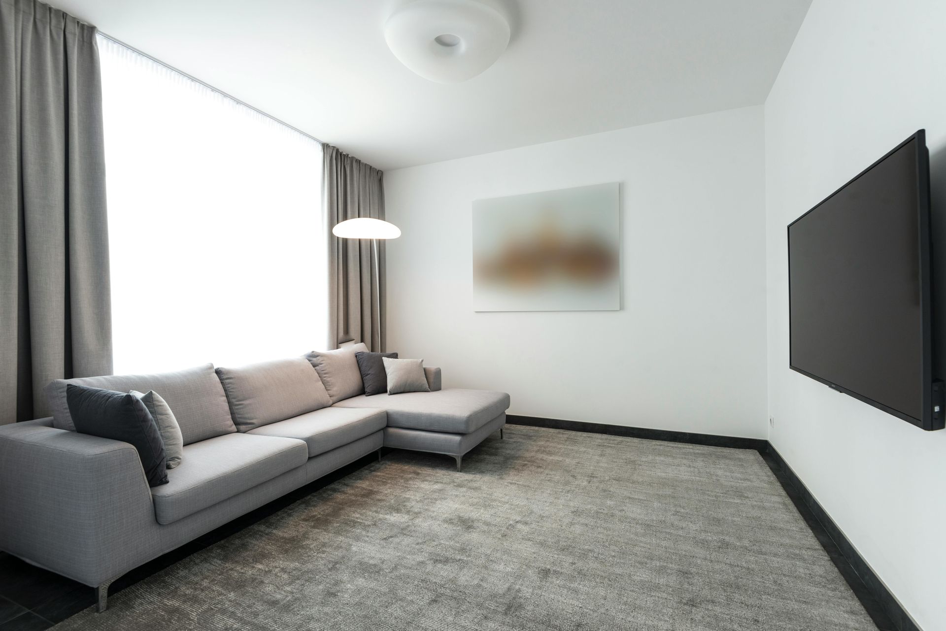 Gray sectional sofa in modern living room with large TV and artwork.
