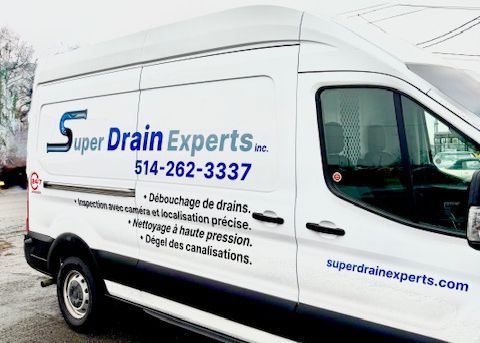 Une camionnette de service blanche pour Super Drain Experts, avec le nom de l'entreprise, son numéro de téléphone et les services proposés indiqués sur le côté.