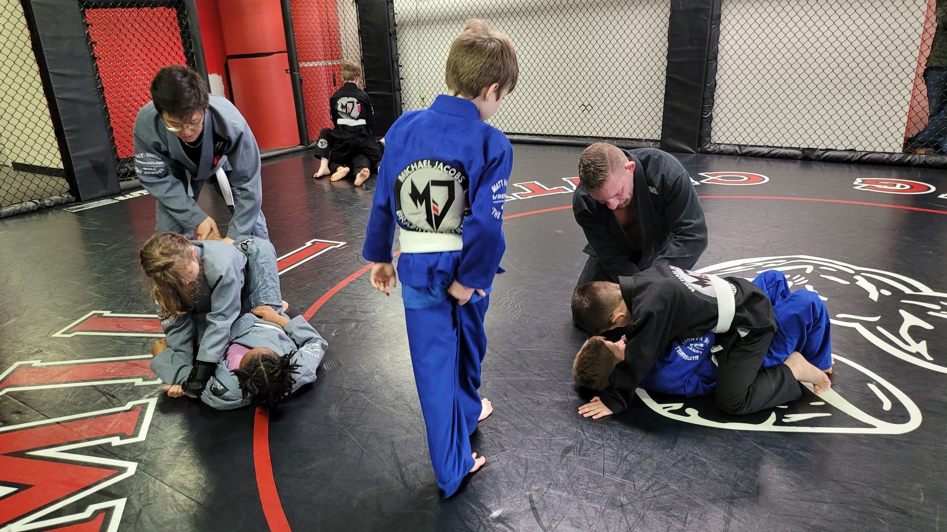 A group of children are practicing jiu jitsu in a gym.