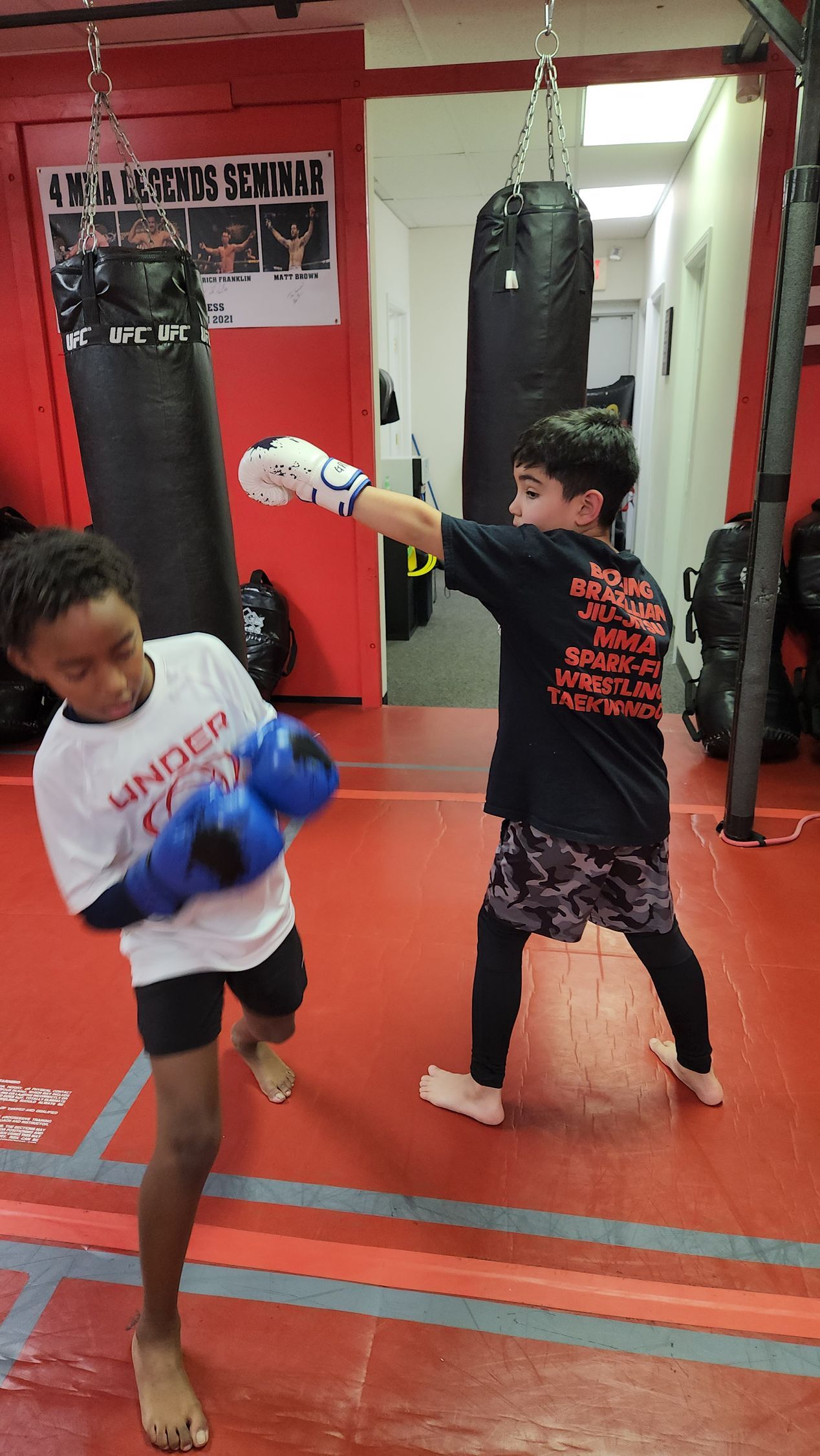 Two young boys are boxing in a gym.