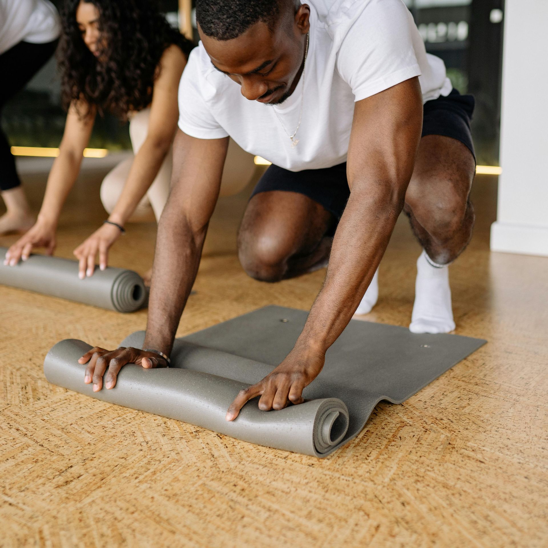 A man is kneeling down on a yoga mat.