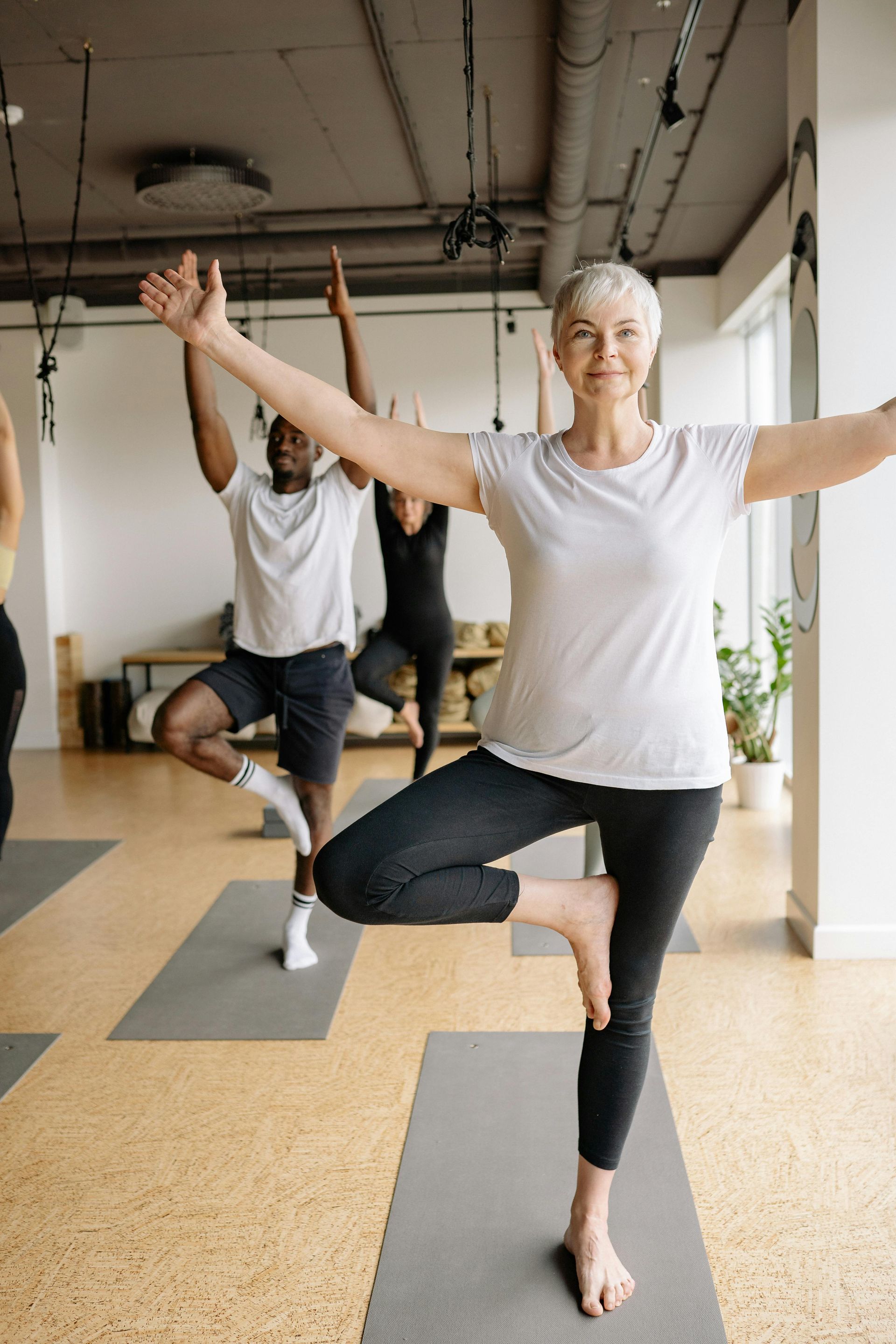 A group of people are doing yoga together in a gym.