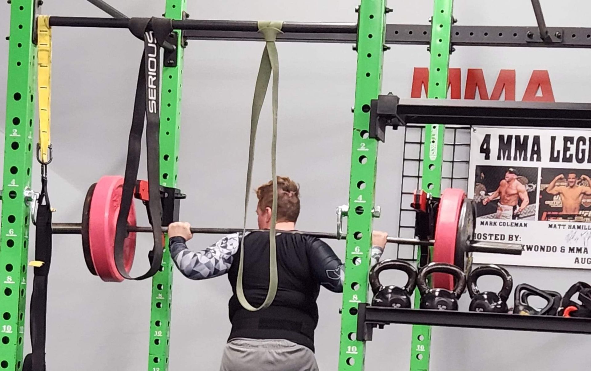 A man squatting in front of a sign that says mma