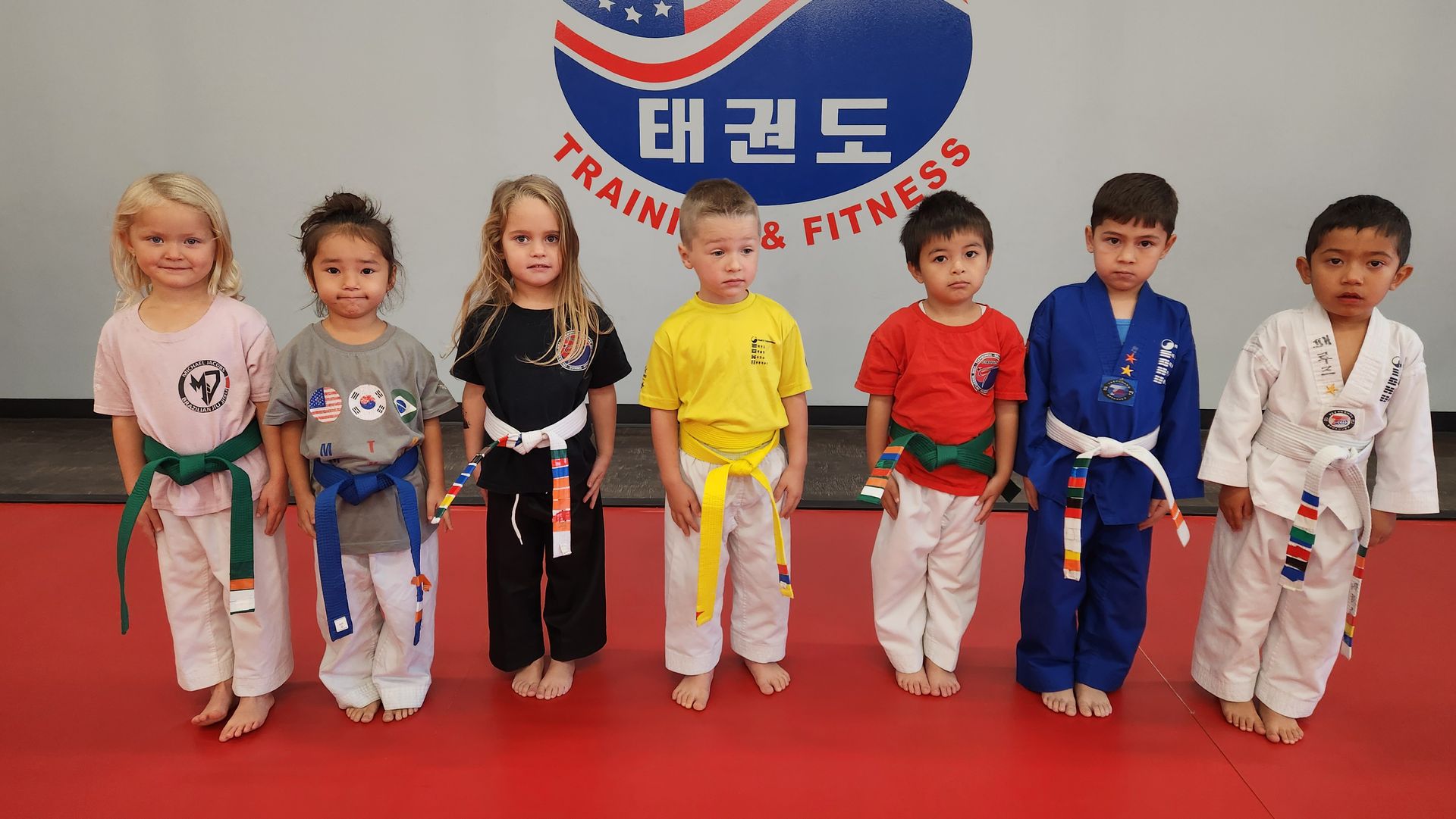 A group of young children in karate uniforms are standing in a line.