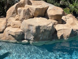 A large rock in the middle of a swimming pool.