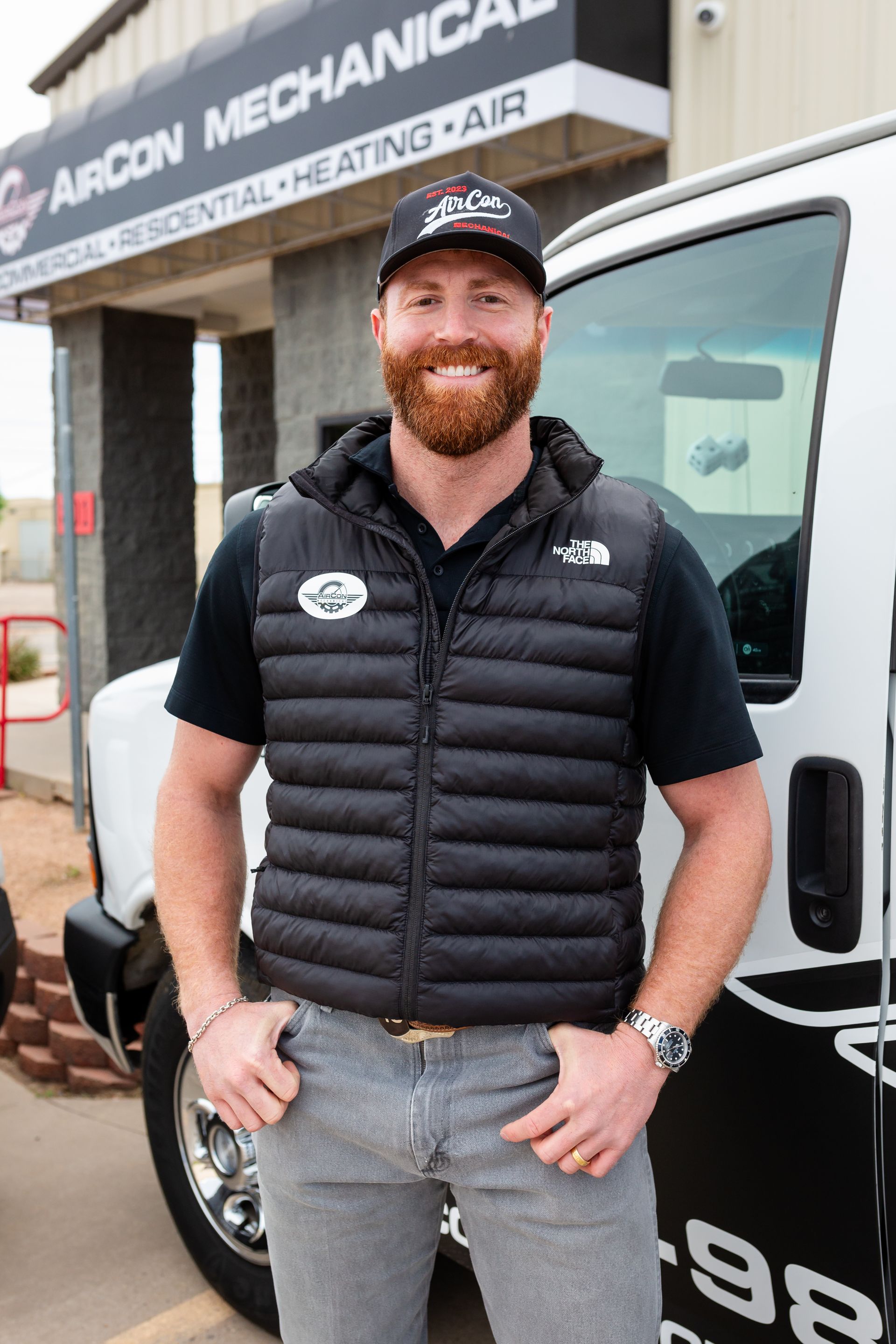 A man with a beard is standing in front of a truck.