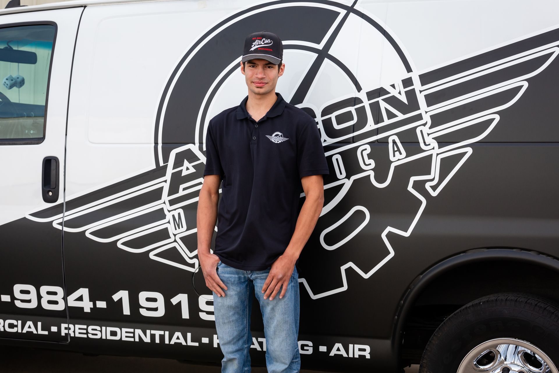 A man is standing in front of a black and white van.