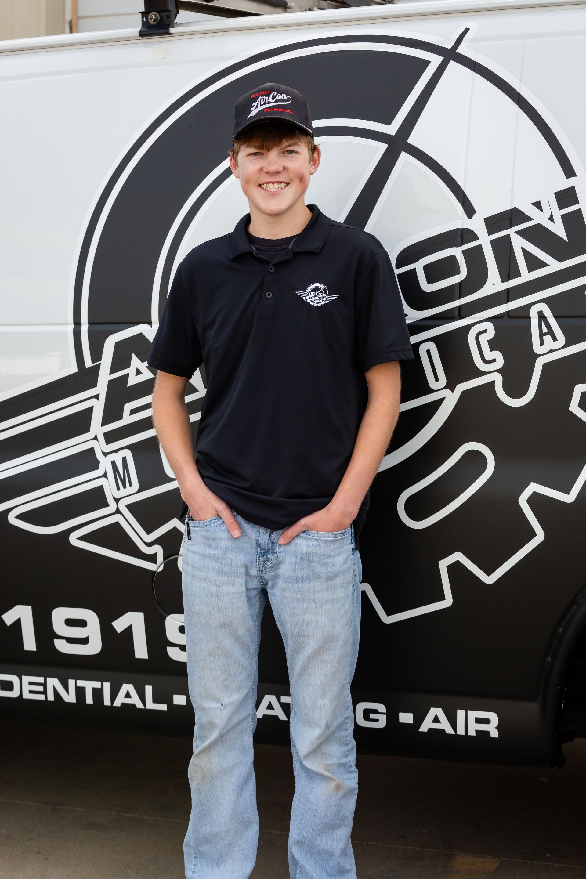 A young man is standing in front of a black and white van.