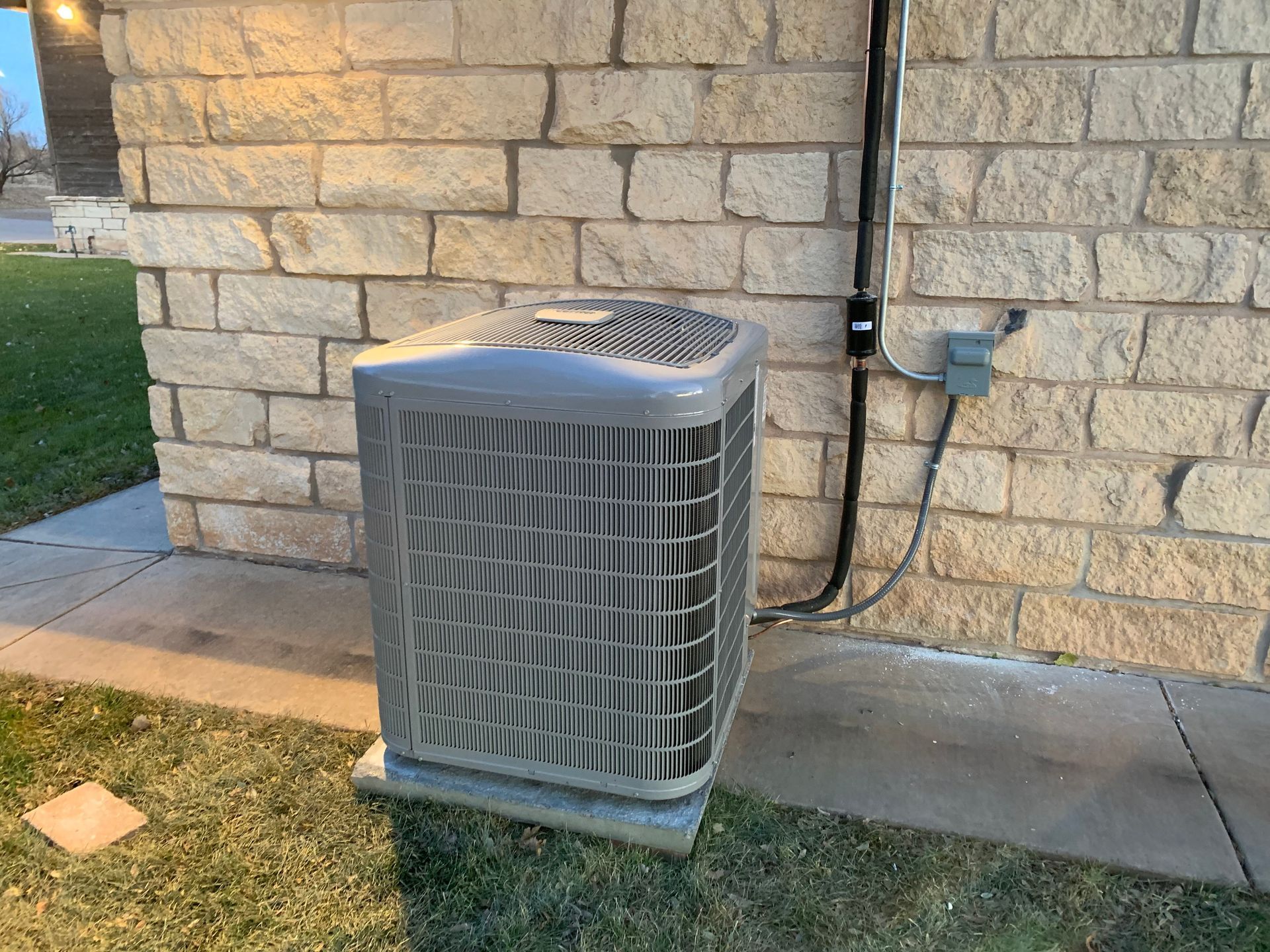 An air conditioner is sitting on the side of a brick building.