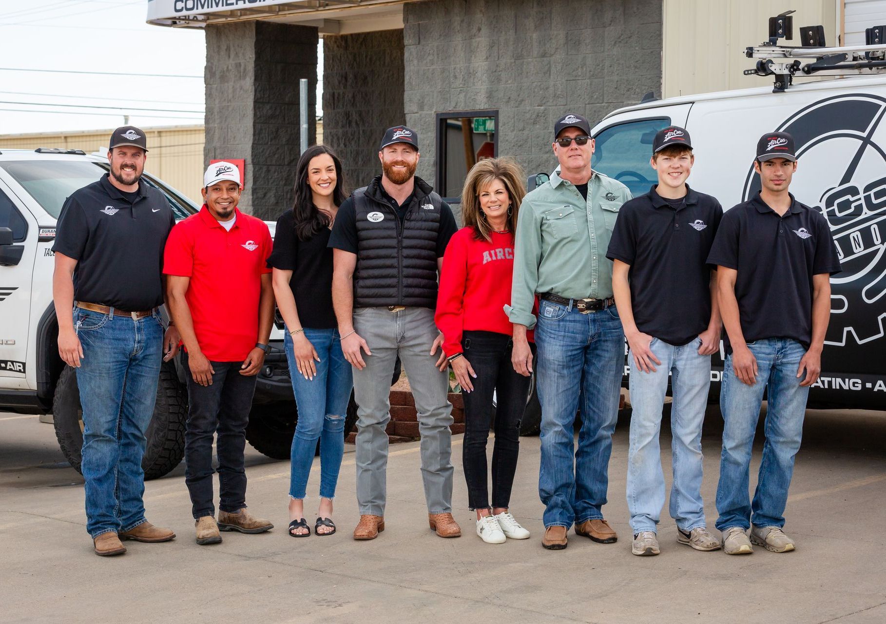 A group of people are posing for a picture in front of a truck.