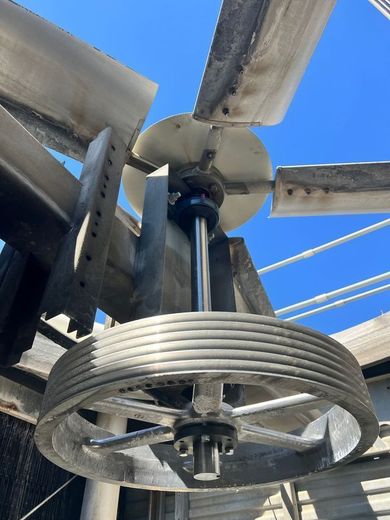 A close up of a metal wheel with a blue sky in the background