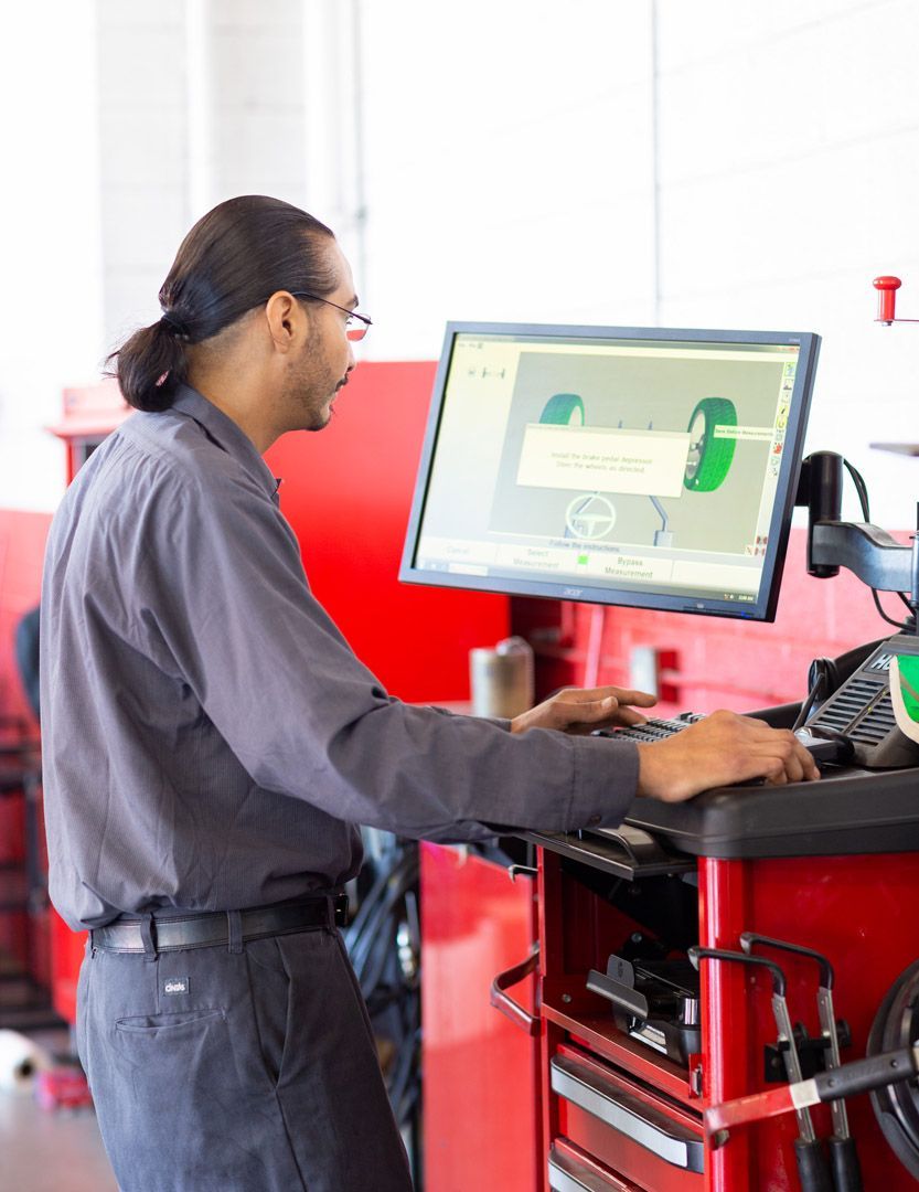 Technician Operating a Wheel Alignment Machine | University Tire & Auto Service