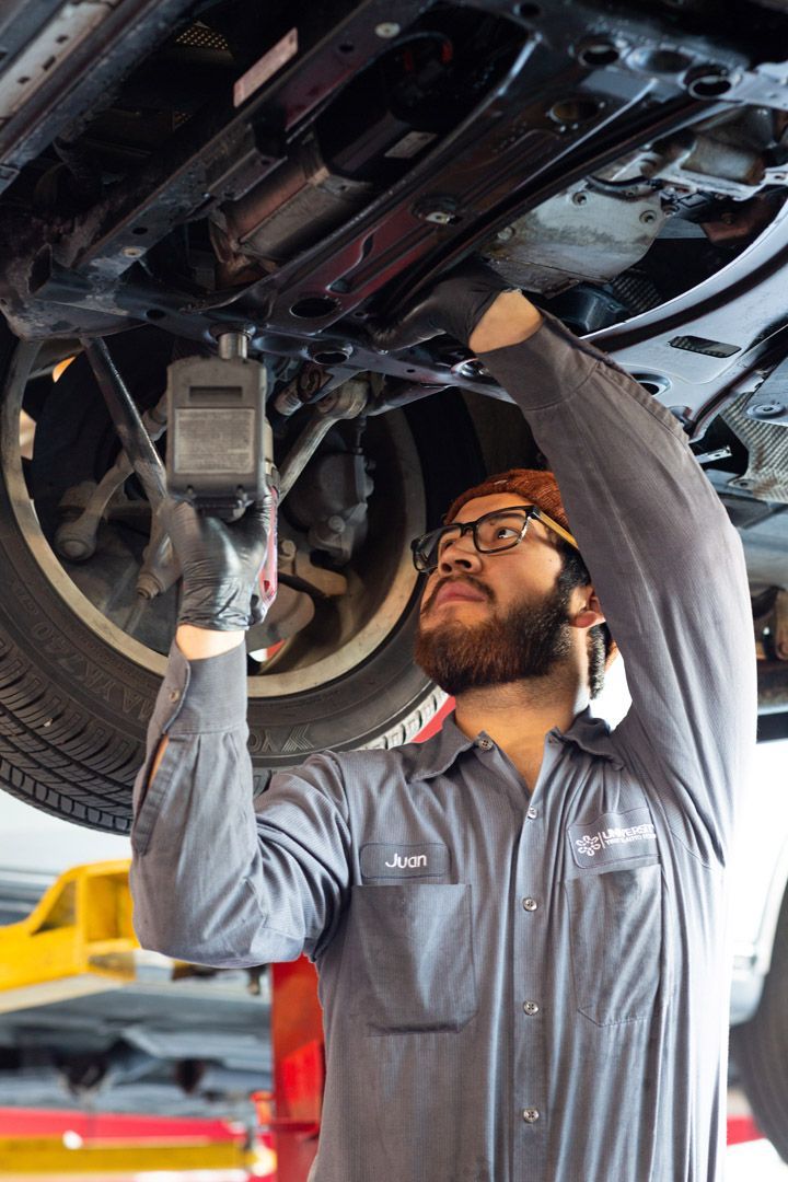 Mechanic Working on a Vehicle's Undercarriage | University Tire & Auto Service