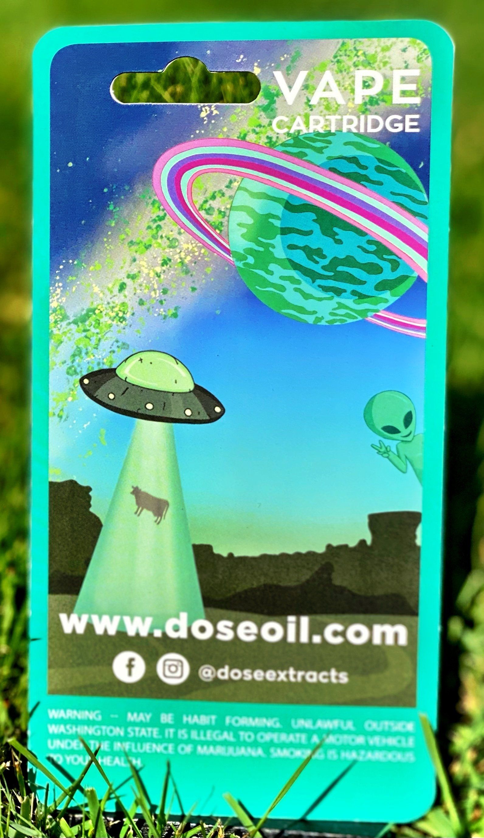 A vape cartridge is sitting on top of a lush green field.