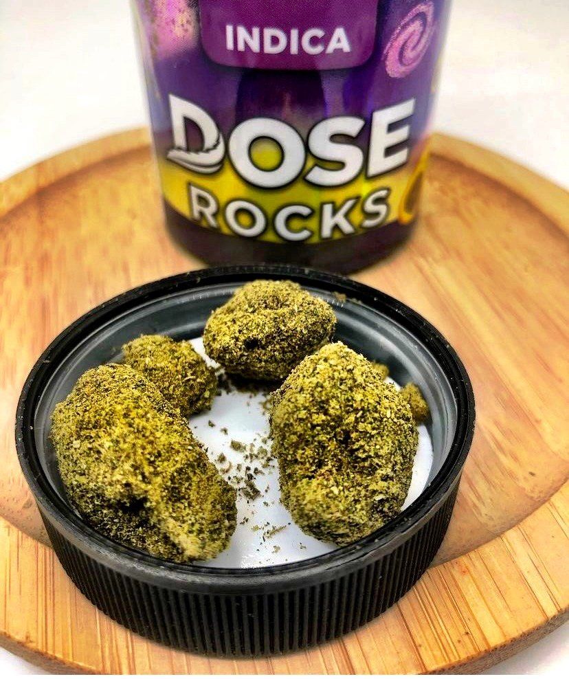 A container of dose rocks sits on a wooden tray