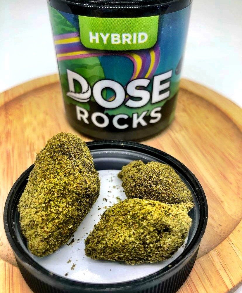 A jar of hybrid dose rocks sitting on top of a wooden tray.