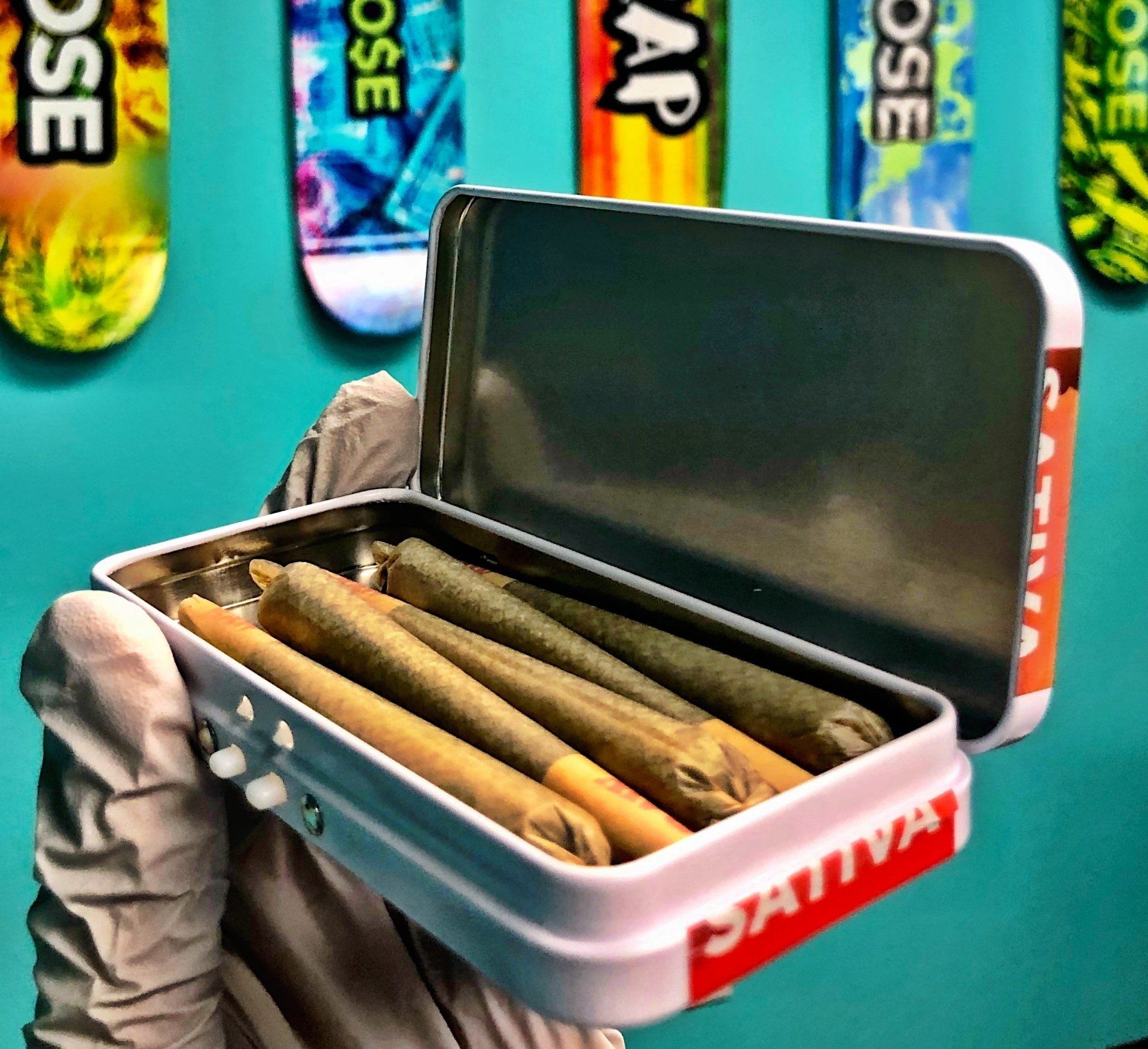 A person is holding a tin of pre rolled joints that says dativa on it