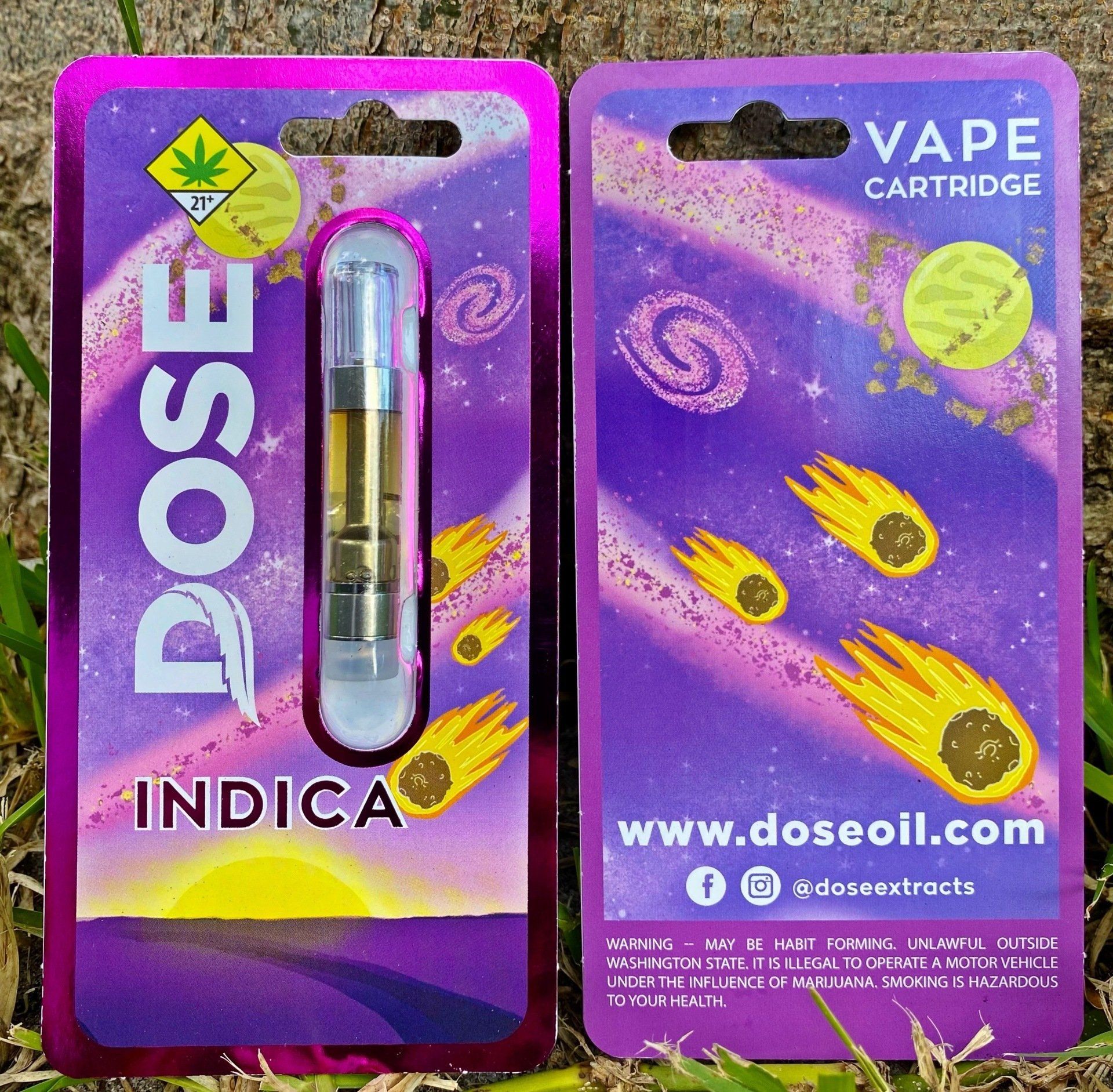 A dose indica vape cartridge sits next to its packaging