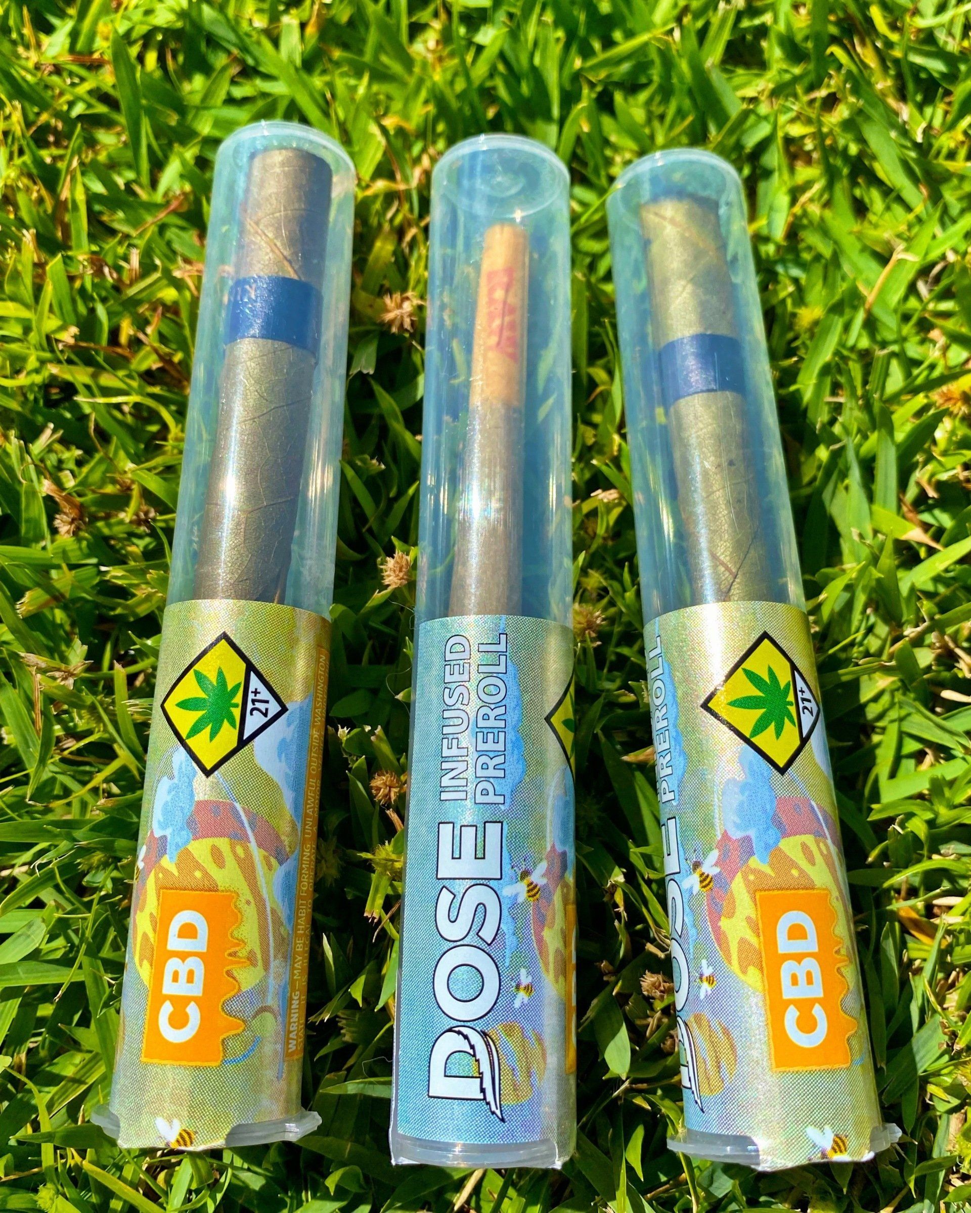 Three tubes of cbd cigarettes are sitting on top of a lush green field.