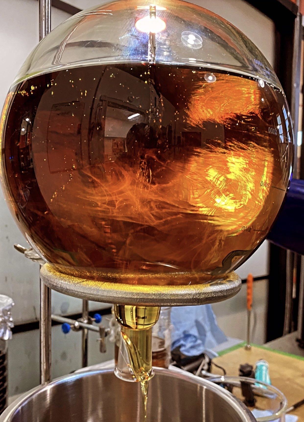A glass ball filled with liquid is being poured into a metal bowl.