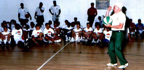A man is holding a volleyball in front of a group of people