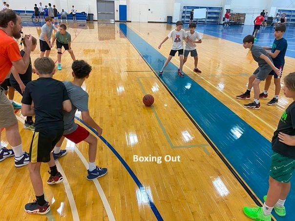 A group of young boys are playing boxing out on a basketball court.