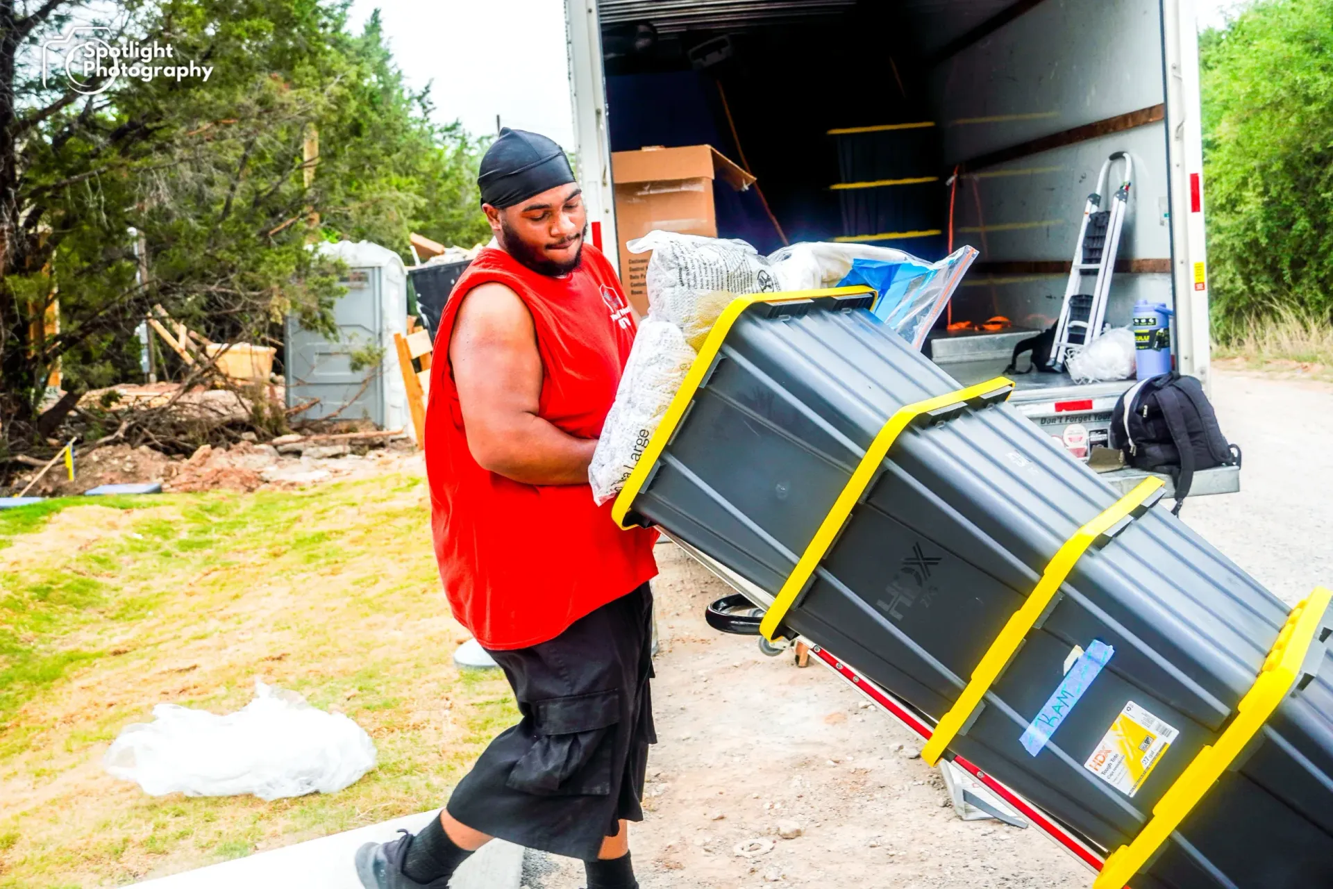 A man in a red shirt is carrying a large black box.