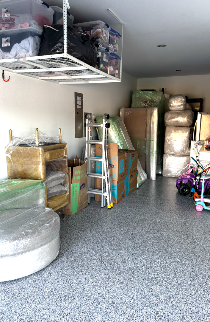 Garage full of packed boxes and furniture, including overhead storage.