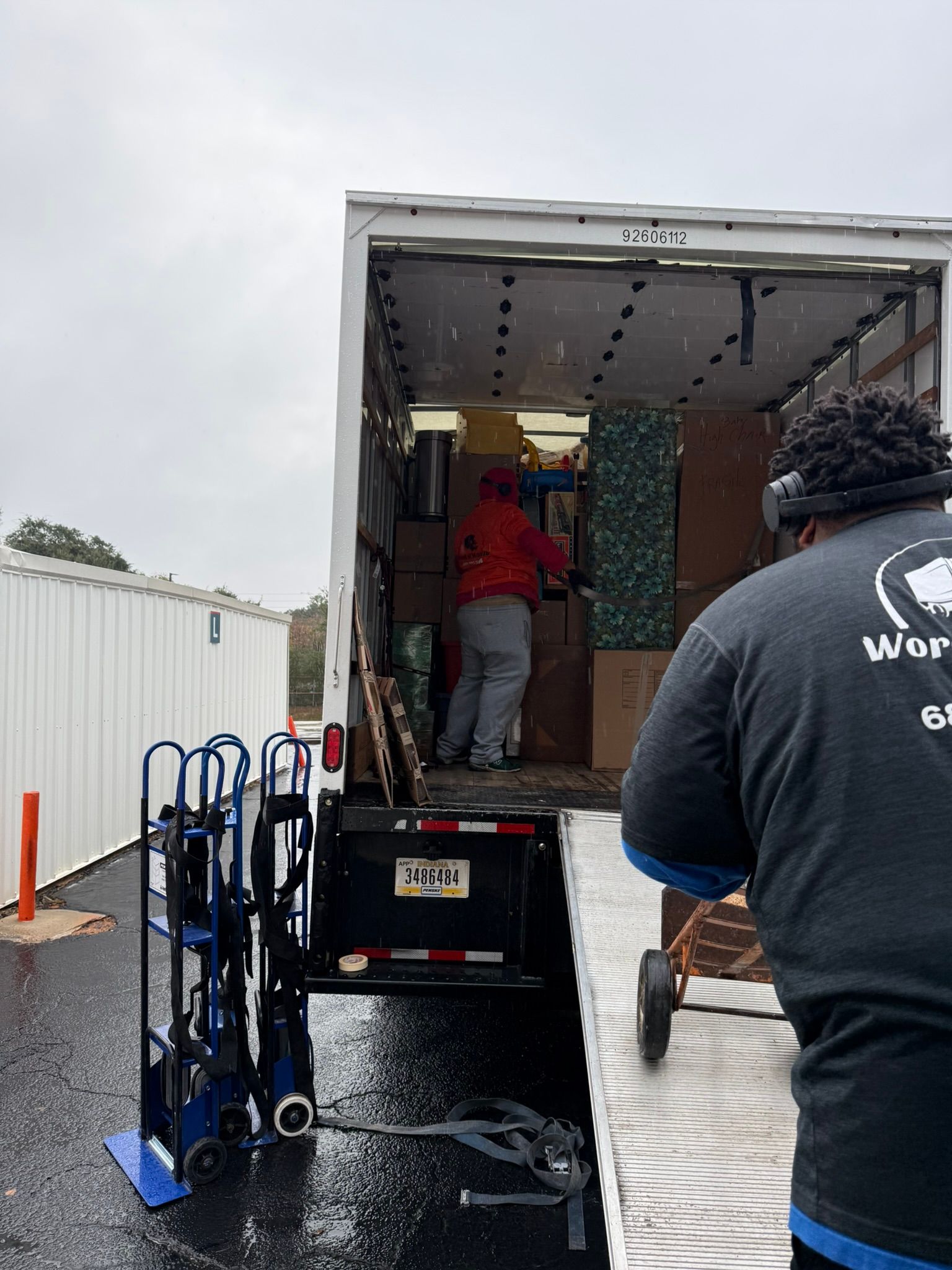Movers loading a truck with boxes and furniture on a rainy day.