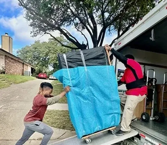 Two men are carrying a large piece of furniture on a dolly