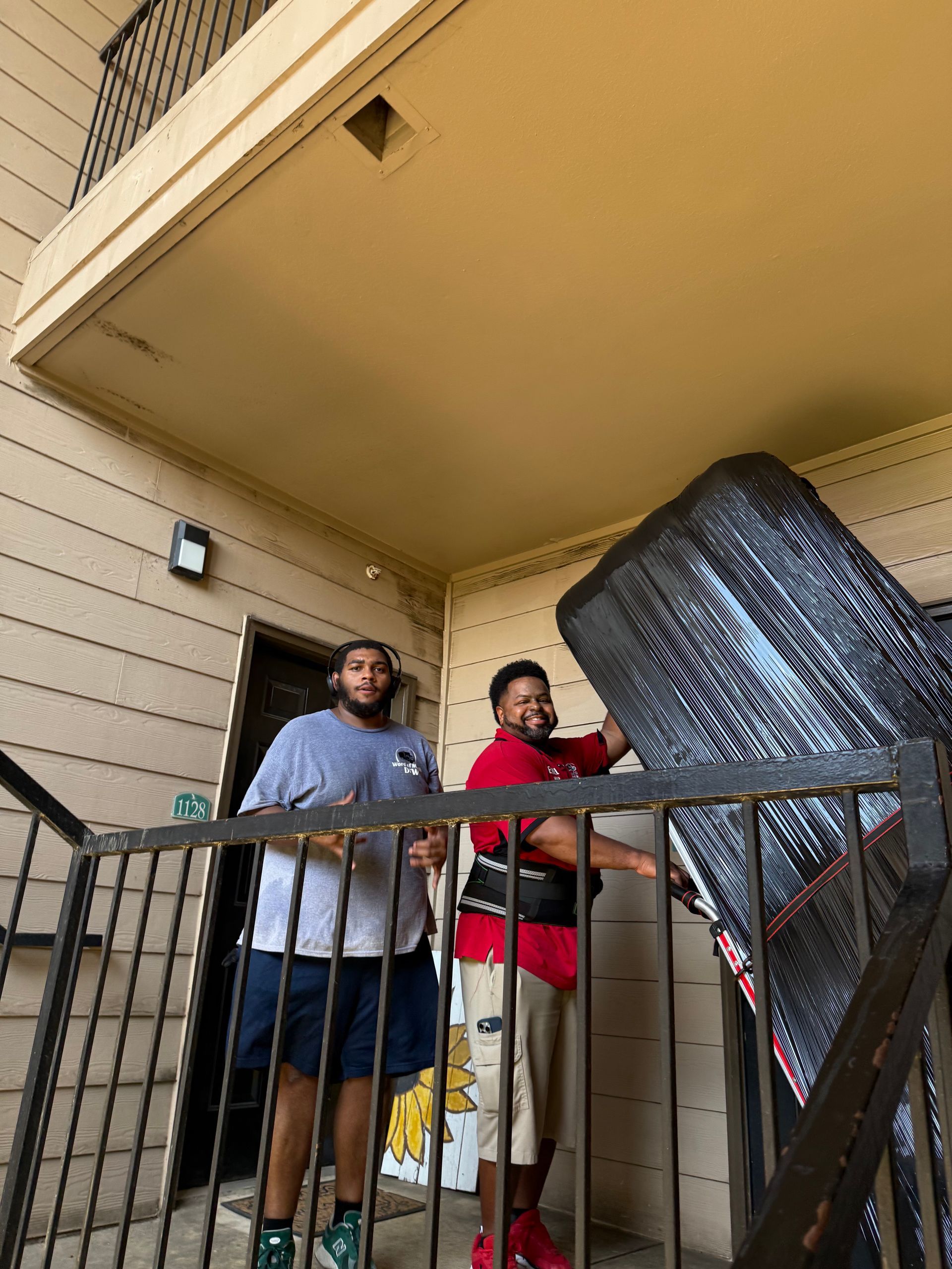 Two men are carrying a large piece of furniture on a dolly