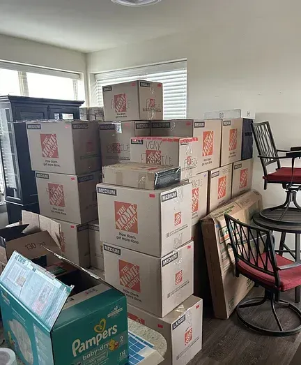 A room filled with lots of moving boxes and a pampers box.