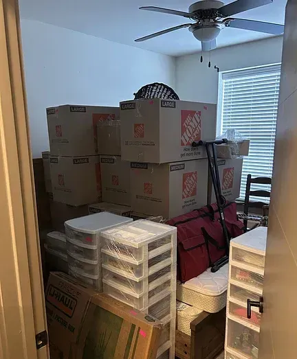 A room filled with boxes and a ceiling fan.