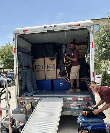 A man is standing in the back of a moving truck.