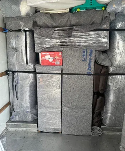 The inside of a moving truck filled with boxes and blankets.