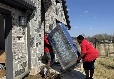 Two men are carrying a refrigerator into a house.