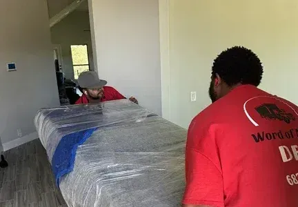 Two men are moving a couch in a living room.