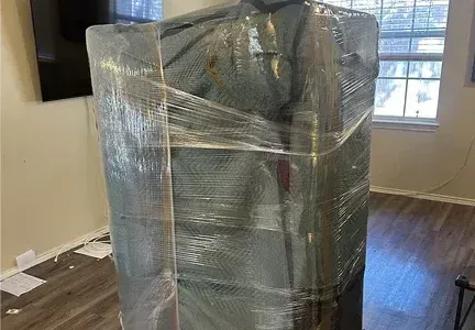 A couch is wrapped in plastic wrap in a living room.